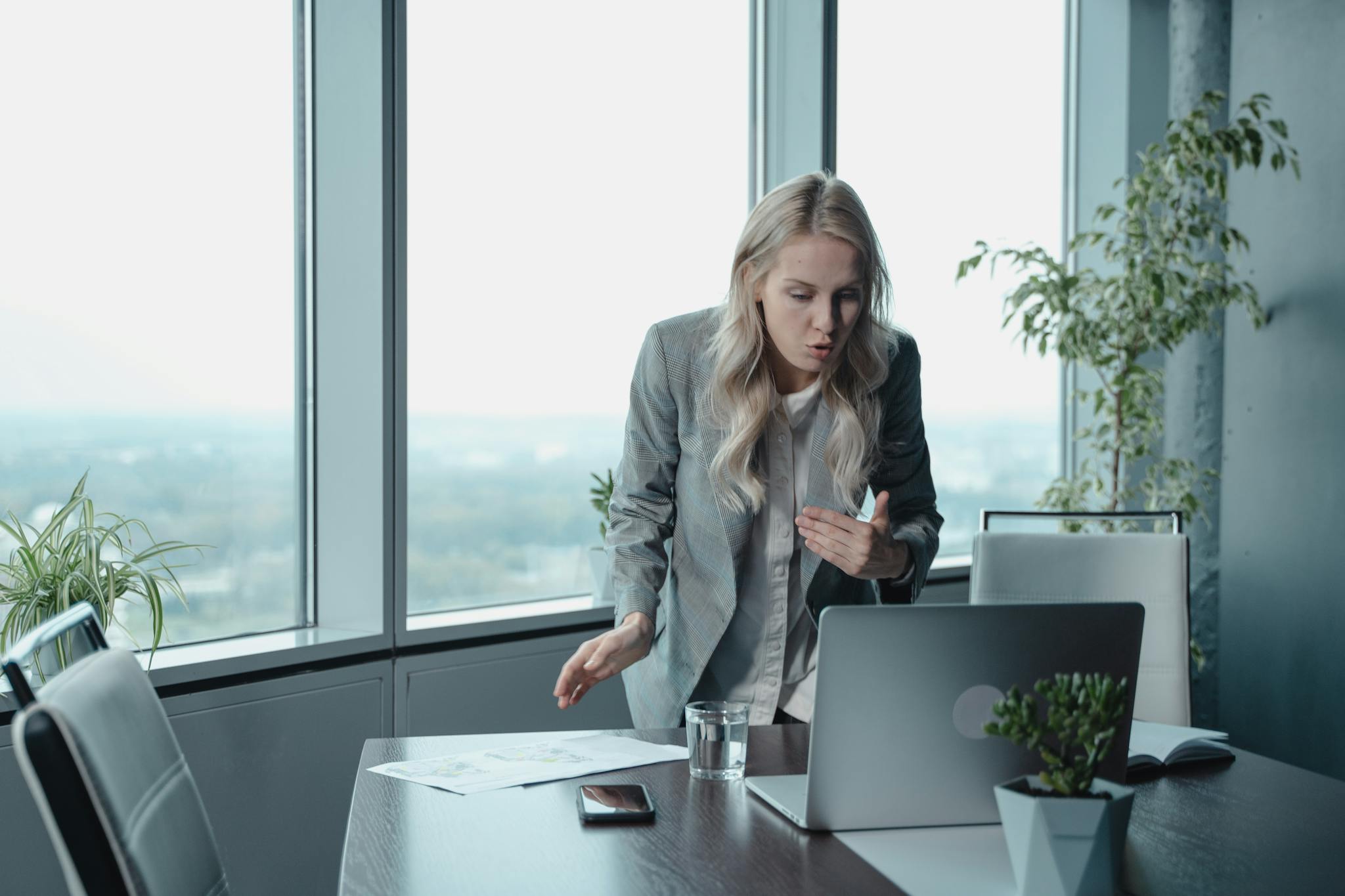 Businesswoman engaging in a video call, demonstrating leadership in a modern office setting.